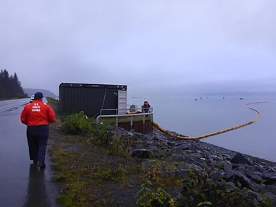 Coast Guard personnel oversee the deployment of boom to protect the Solomon Gulch fish hatchery.
