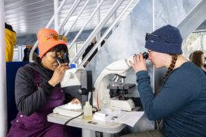 Two students from Prince William Sound College use microscopes to examine water samples taken during the trip.  