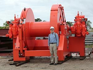 Council volunteer Jim Herbert stands next to large winches waiting to be installed on a tug headed for Alaska.